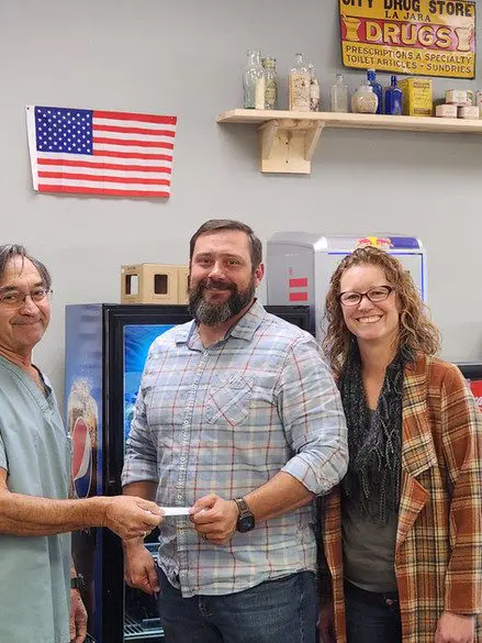 A man and two women holding a wii controller.