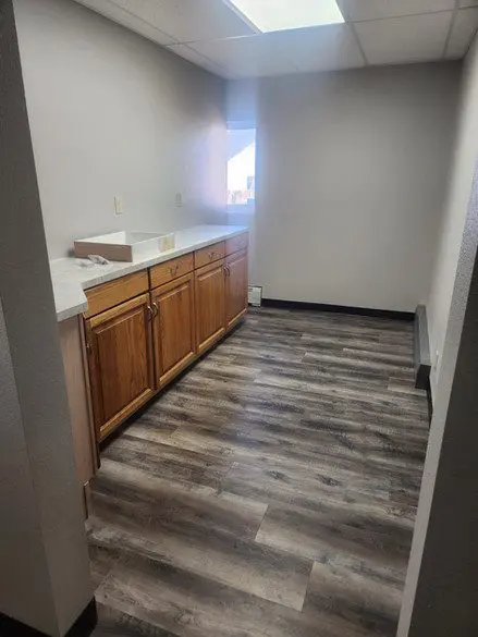 A kitchen with wood floors and white walls.