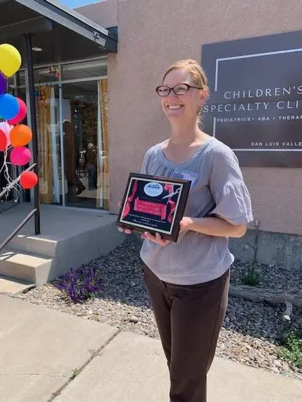 A woman holding a box of chocolates outside.