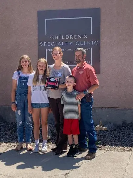 A family posing for a picture in front of the children 's specialty clinic.