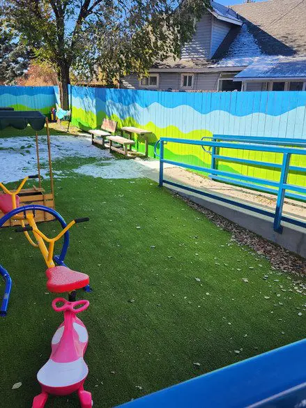 A playground with several different colored swings and benches.